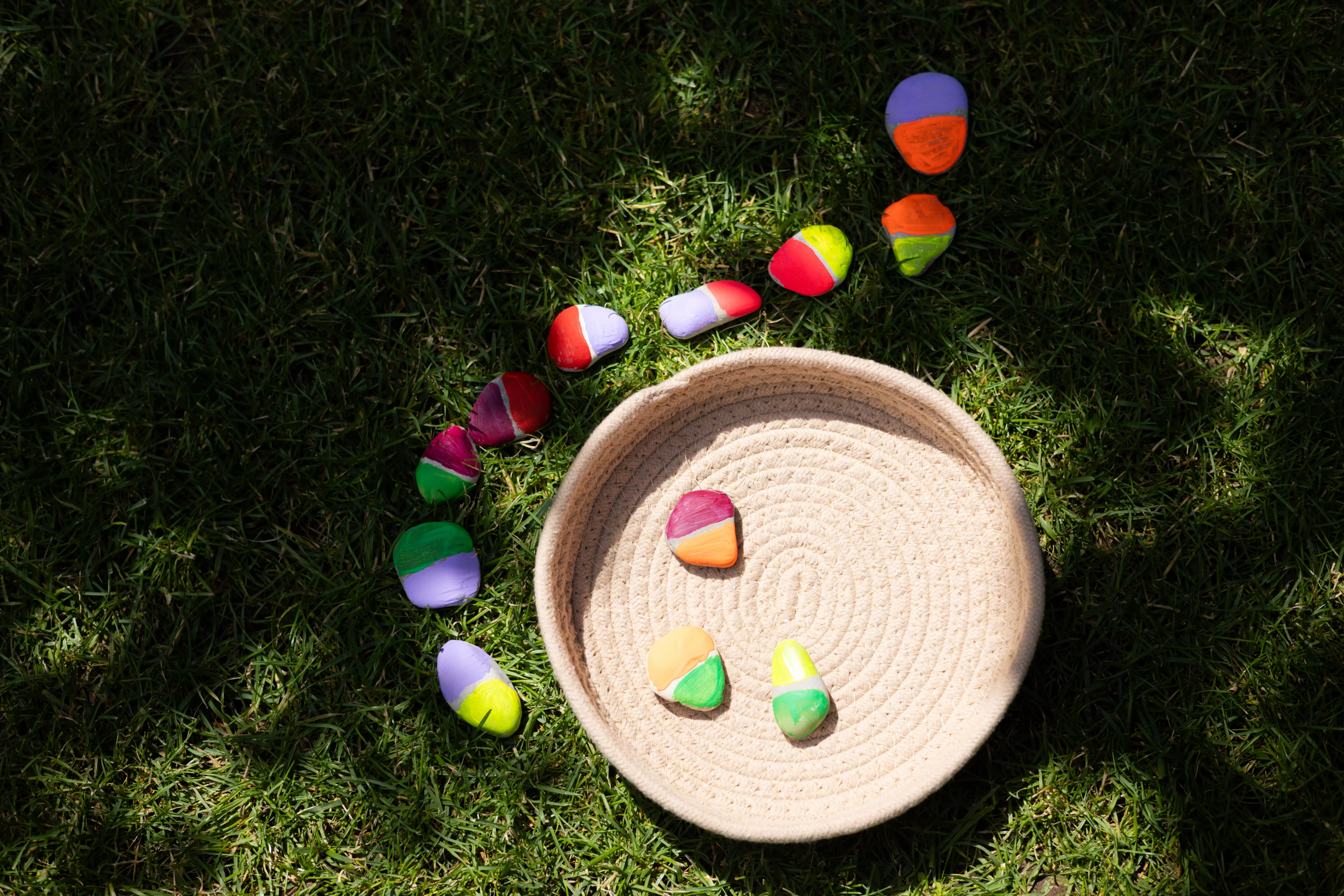 Beim Spaziergang sammeln Kinder flache Steine, die später mit Acrylfarben bemalt werden. Nach dem Trocknen legen sie eine riesige Domino-Kette damit an, ein kreatives Outdoor-Spiel, das Spaß und Kreativität fördert.