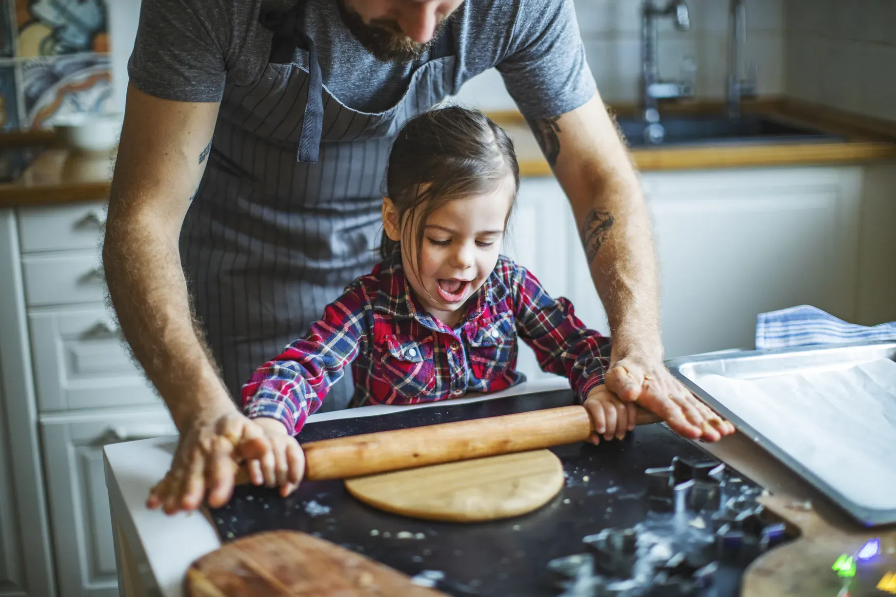 Der Herbst ist ideal, um mit der ganzen Familie Kürbisrezepte zu erkunden. Ein Kind und sein Vater haben Spaß beim Ausrollen des Kürbisteigs. Kürbisse sind vielseitig und bieten viele Möglichkeiten für einfache und kinderfreundliche Rezepte, die Spaß machen und schmecken. Entdecke fünf solcher Rezepte für gemeinsame Kochmomente.