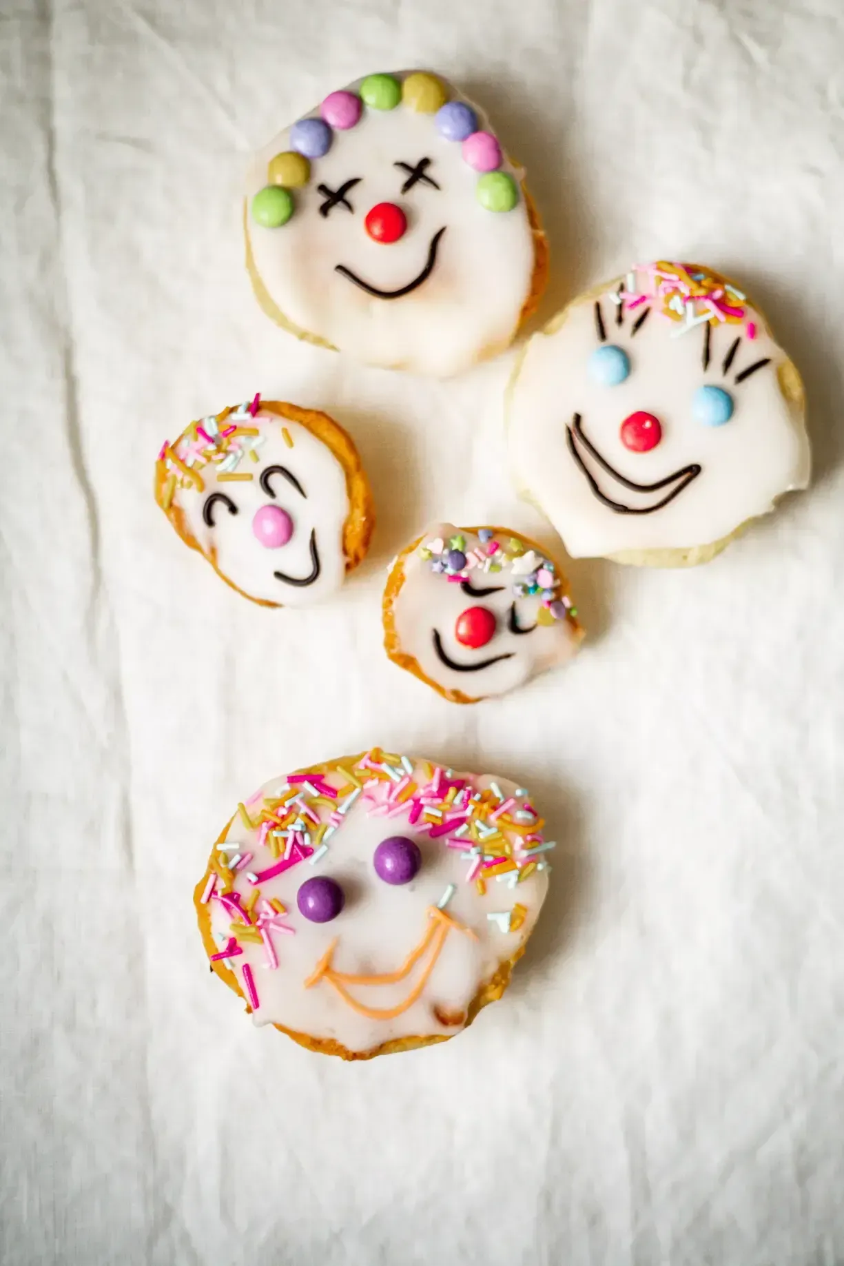 Leckere_Amerikaner:Bunte Clownamerikaner, die mit Streuseln und Zuckerschrift verziert sind